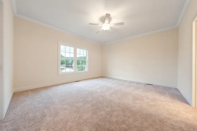 an empty room with chandelier fan and windows