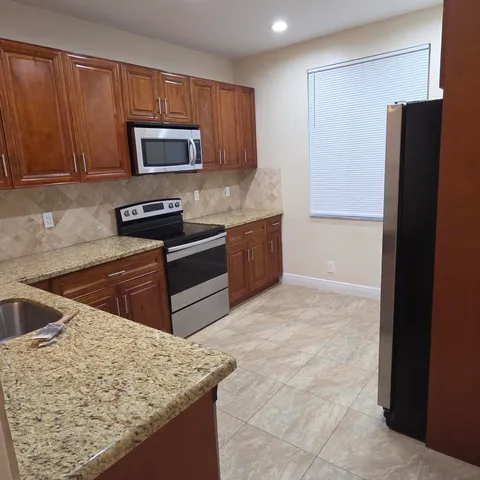 a kitchen with stainless steel appliances granite countertop a stove microwave and refrigerator