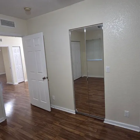 a view of empty room with wooden floor and fan