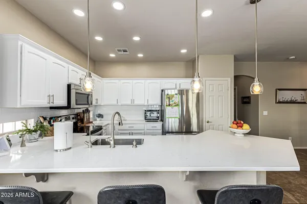 a kitchen with kitchen island granite countertop a sink a refrigerator and a stove