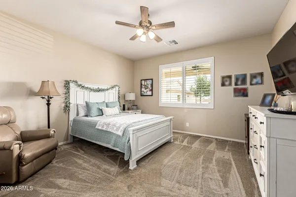 a bedroom with a bed a couch and a flat tv screen on the dresser