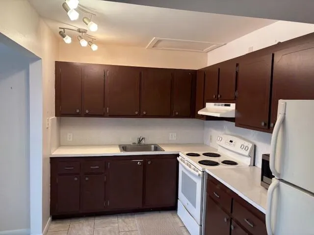 a kitchen with kitchen island a stove a sink and a refrigerator with wooden cabinets