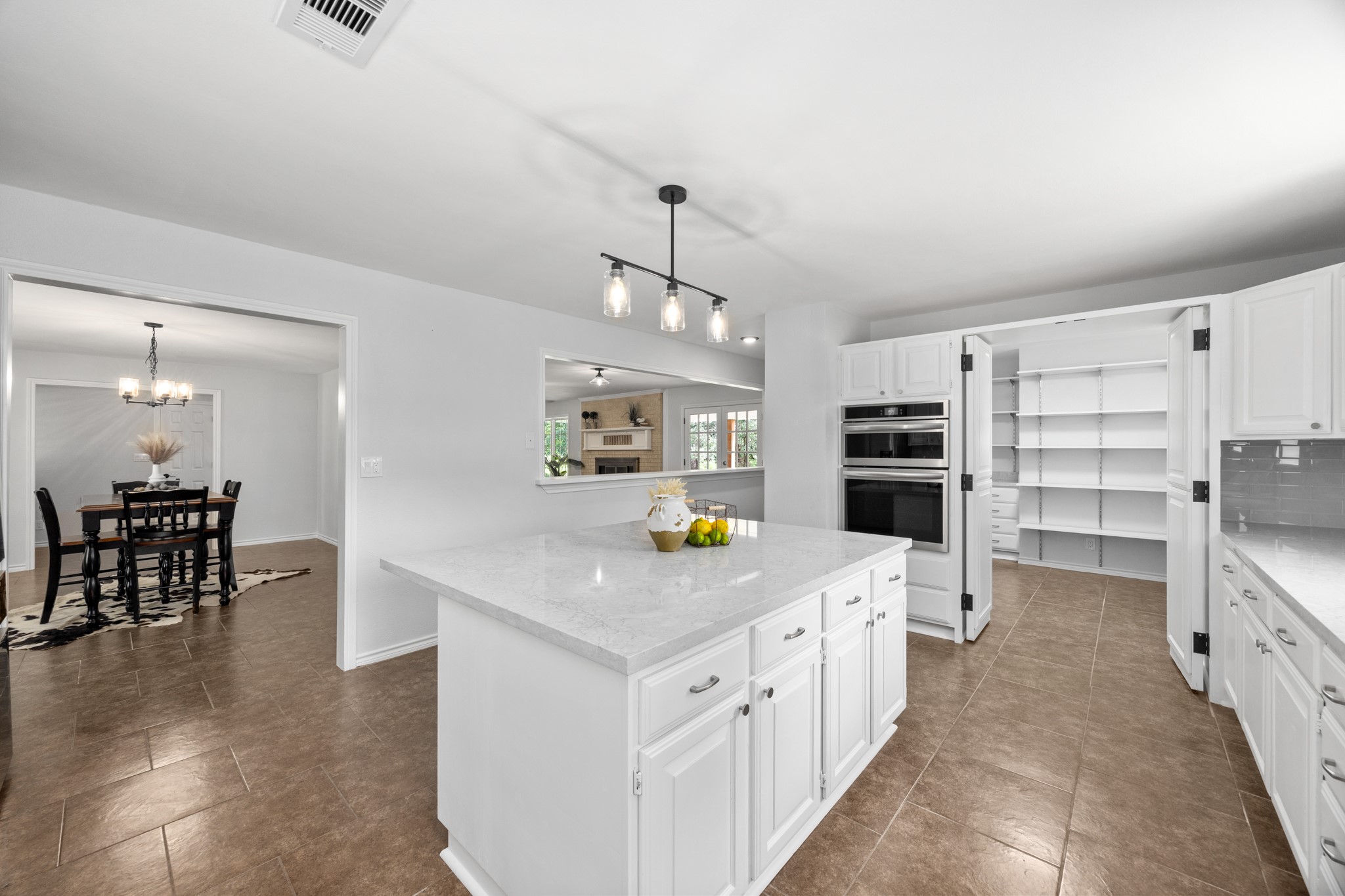10209 Oberrender Road Needville, TX 77461 - Photo 16 of 50 This modern kitchen features a spacious island with white cabinetry, ample storage, and all new stainless steel appliances. It opens to a dining area with elegant lighting and an adjacent living room, creating a bright and inviting space.