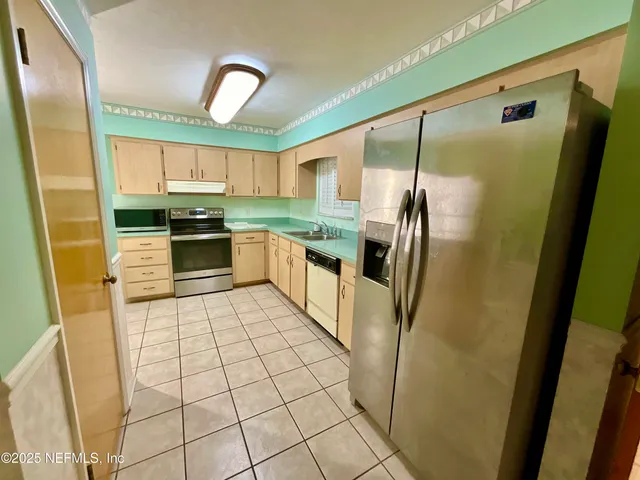 a kitchen with stainless steel appliances granite countertop a refrigerator a stove and a sink