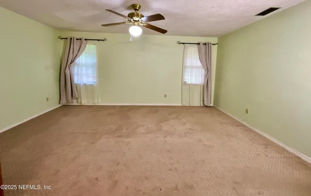an empty room with a ceiling fan and a window