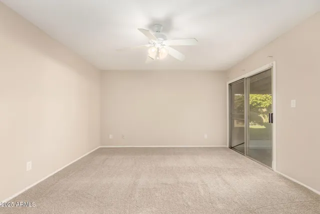 an empty room with a ceiling fan and window