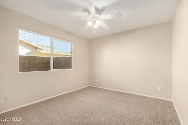 an empty room with a window and a fan