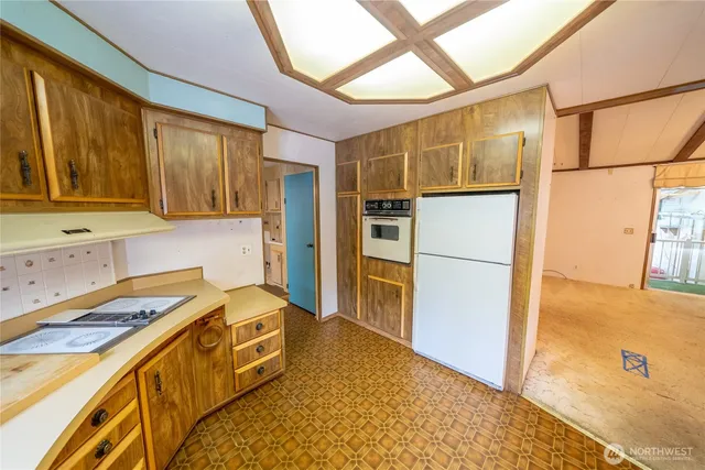 a kitchen that has a refrigerator a stove and a sink with wooden floor