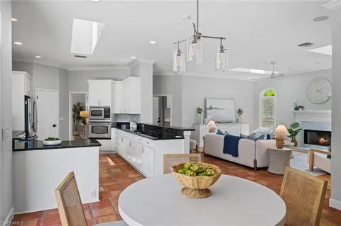 a living room with furniture kitchen view and a chandelier