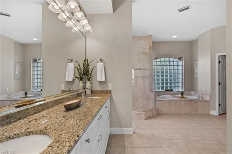 a bathroom with a granite countertop sink a large mirror and a bathtub
