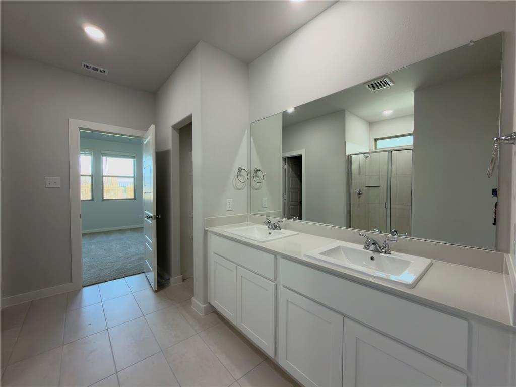 120 Millwood Road Lavon, TX 75166 - Photo 27 of 34 Dual vanity with white cabinetry and integrated sinks, a large wall-mounted mirror, and tile flooring