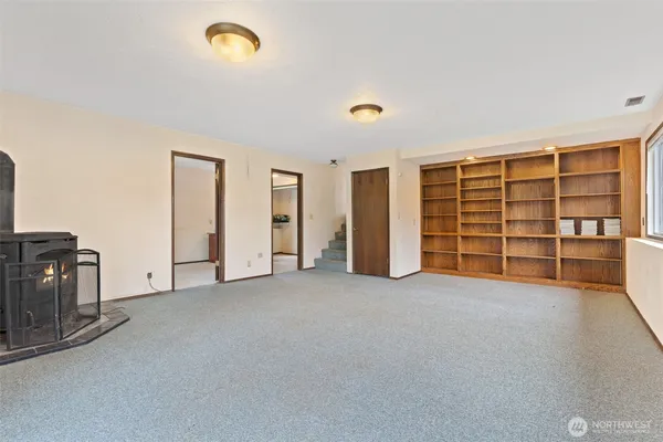 a view of an empty room with a window and a kitchen