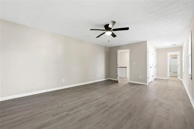 a view of empty room with wooden floor and ceiling fan