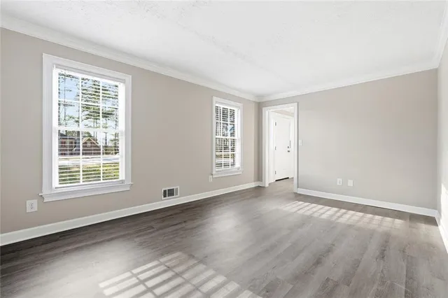 an empty room with wooden floor and windows