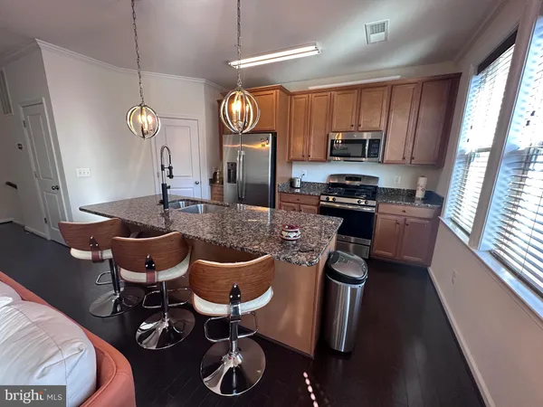 a kitchen with stainless steel appliances granite countertop a stove top oven a refrigerator a sink dishwasher a dining table and chairs with wooden floor