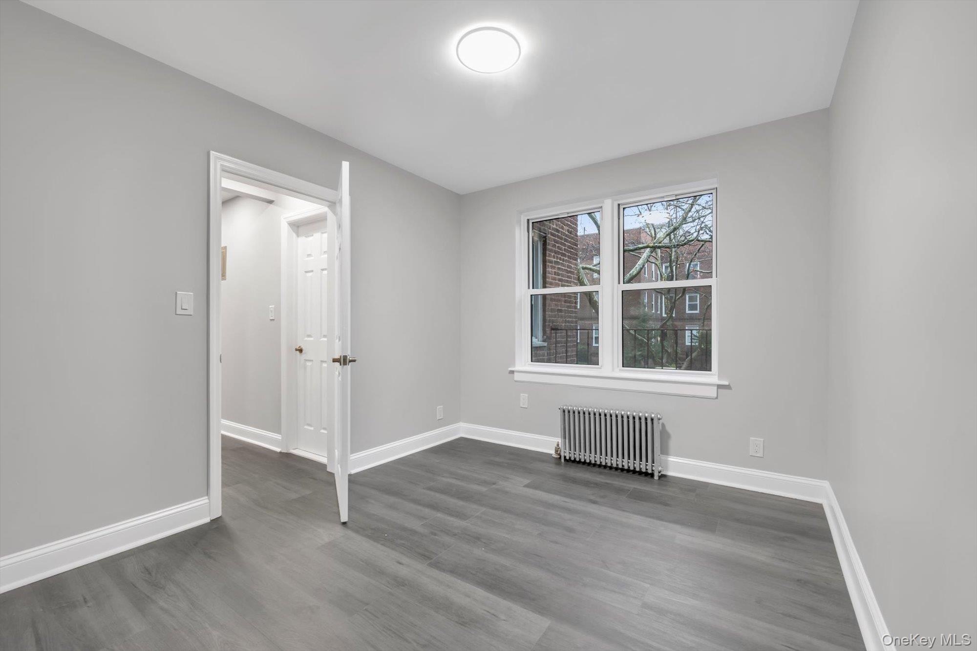 79-06 Main Street, Unit 2J Queens, NY 11367 - Photo 11 of 12 an empty room with wooden floor and windows