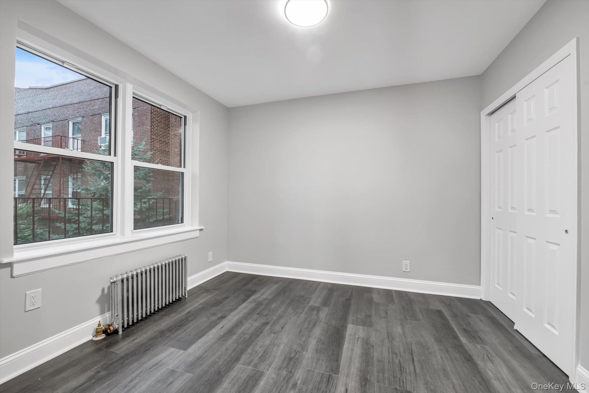 79-06 Main Street, Unit 2J Queens, NY 11367 - Photo 12 of 12 a view of an empty room with wooden floor and a window