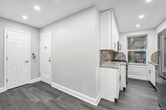 a kitchen with a refrigerator and white cabinets