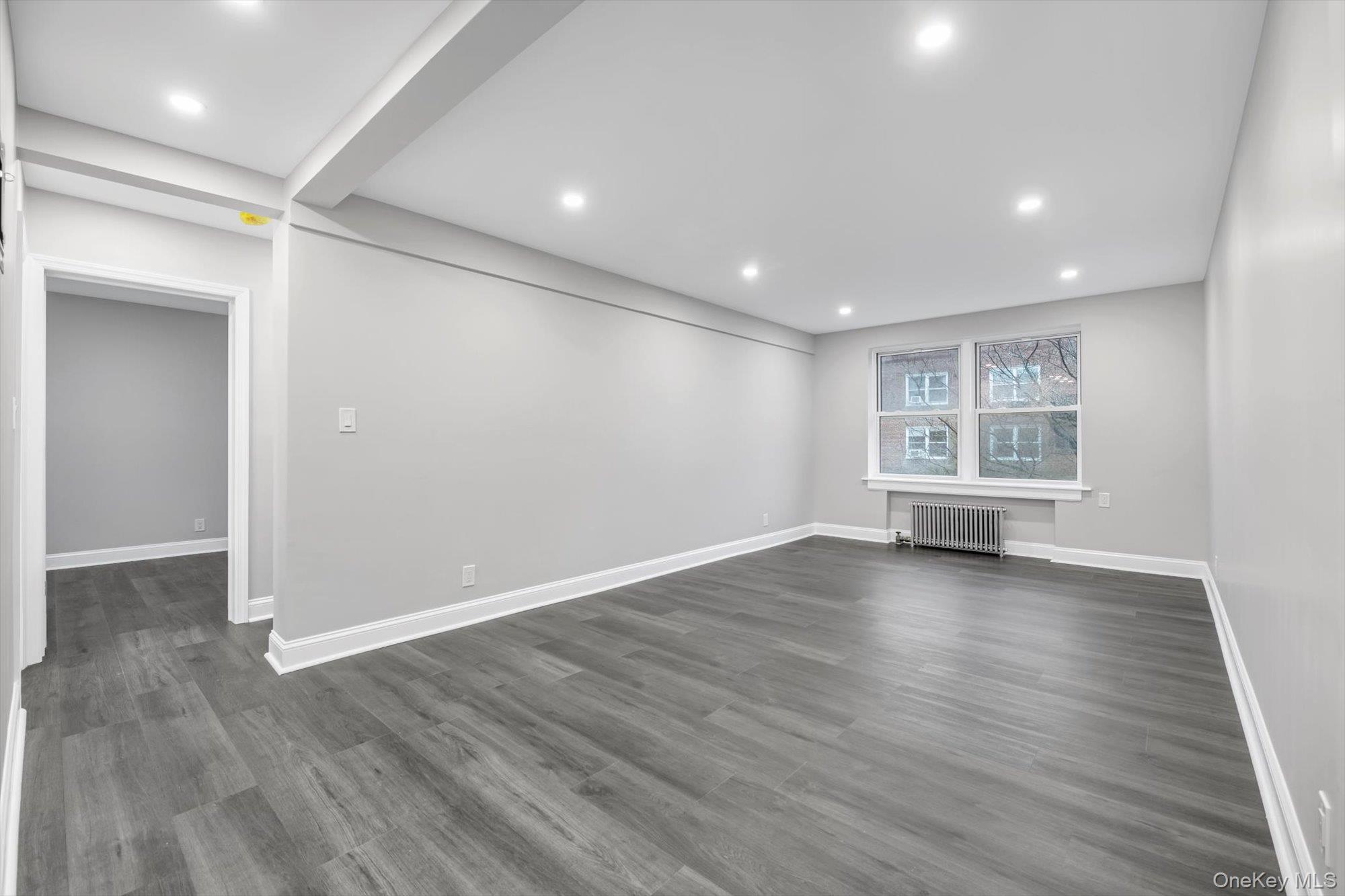 79-06 Main Street, Unit 2J Queens, NY 11367 - Photo 6 of 12 an empty room with wooden floor and windows