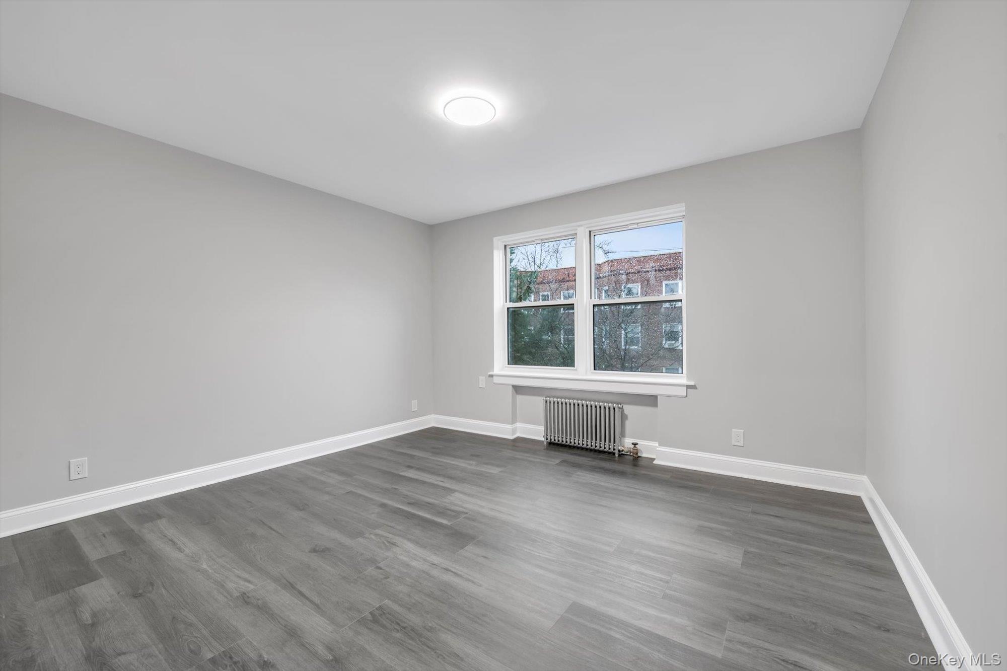 79-06 Main Street, Unit 2J Queens, NY 11367 - Photo 9 of 12 an empty room with wooden floor and a window