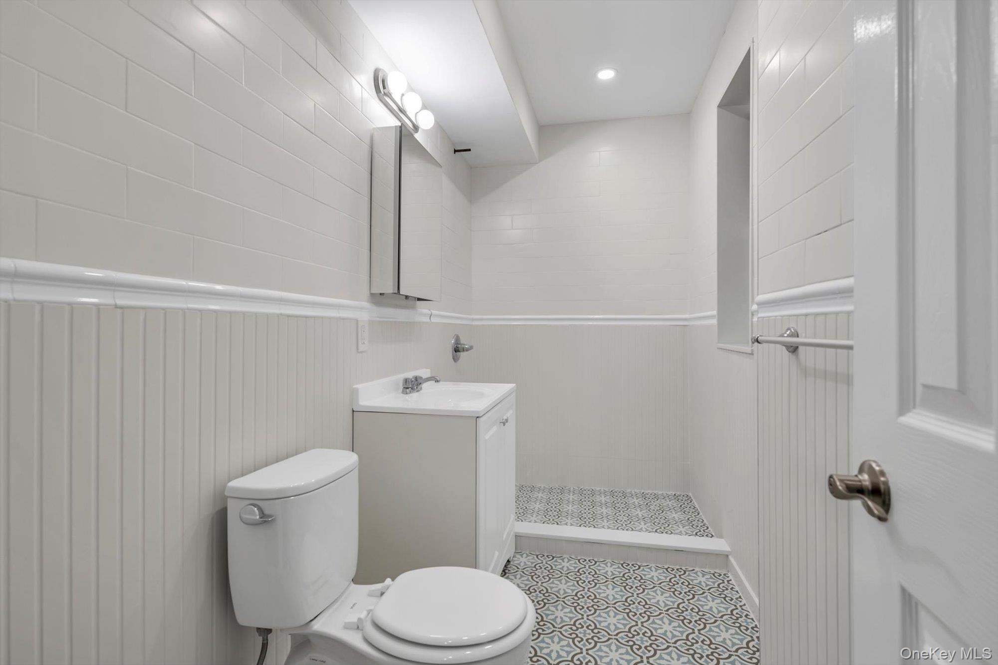 79-06 Main Street, Unit 2J Queens, NY 11367 - Photo 10 of 12 a bathroom with a toilet a sink and mirror