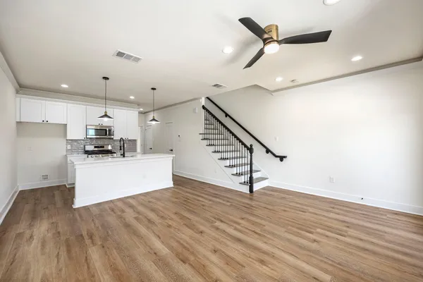 a kitchen with stainless steel appliances kitchen island a wooden floor and white cabinets
