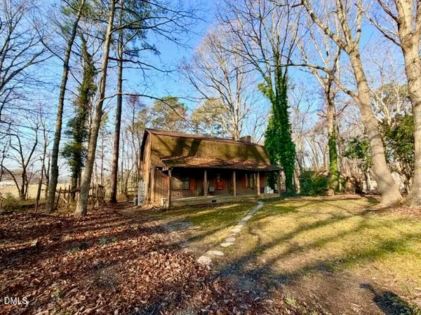 a view of a house with a large tree and a yard in the background
