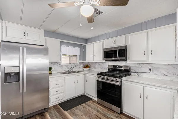 a kitchen with a refrigerator a stove cabinets and wooden floor