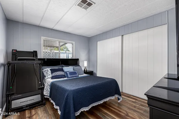 a bedroom with a bed and a flat tv screen on dresser