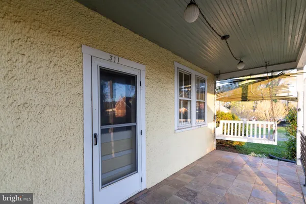 a view of a yard in front of a house with plants and large tree