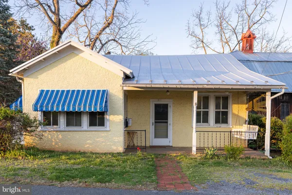 a view of a house with a yard plants and large tree
