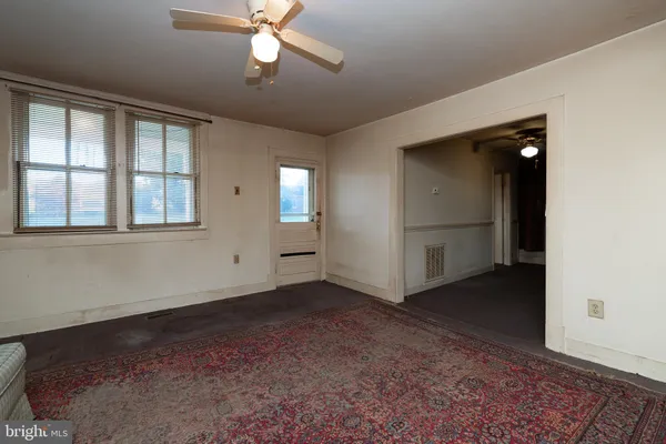 an empty room with windows and fan