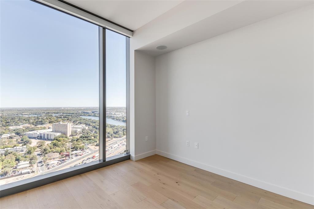 44 East Avenue, Unit 3109 Austin, TX 78701 - Photo 11 of 37 Unfurnished room featuring a city view, wood finished floors, baseboards, and expansive windows