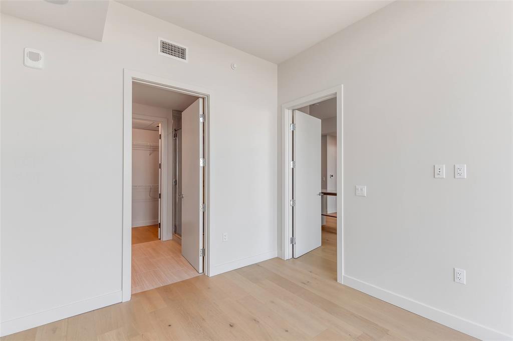 44 East Avenue, Unit 3109 Austin, TX 78701 - Photo 21 of 37 Unfurnished bedroom with a walk in closet, baseboards, visible vents, and light wood-type flooring