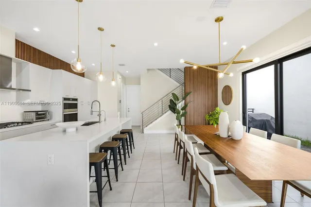 a kitchen with stainless steel appliances kitchen island granite countertop a table chairs and a refrigerator