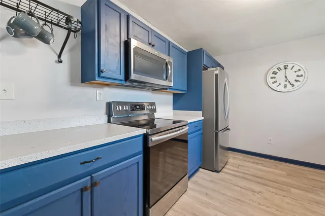 a kitchen with stainless steel appliances granite countertop a sink a stove and a microwave oven on the wooden floor