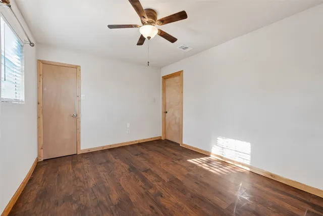 an empty room with wooden floor and a ceiling fan