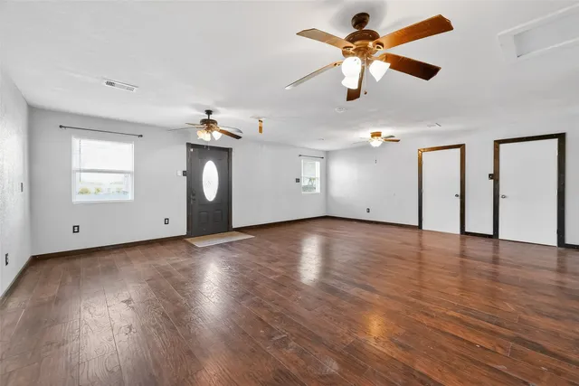 a view of an empty room with window and wooden floor