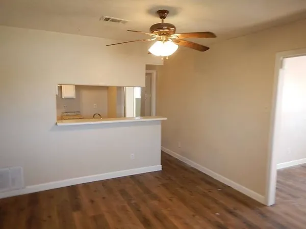 an empty room with wooden floor fan and windows