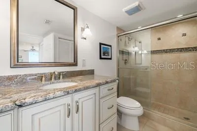 a bathroom with a granite countertop sink a toilet and a mirror
