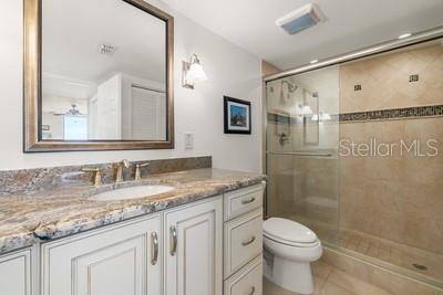 9425 Blind Pass Road, Unit 408 St. Pete Beach, FL 33706 - Photo 11 of 57 a bathroom with a granite countertop sink a toilet and a mirror