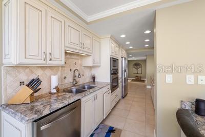 9425 Blind Pass Road, Unit 408 St. Pete Beach, FL 33706 - Photo 19 of 57 a kitchen with granite countertop a sink stainless steel appliances and cabinets