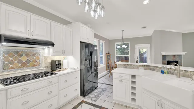 a large white kitchen with granite countertop a stove a sink a refrigerator and cabinets