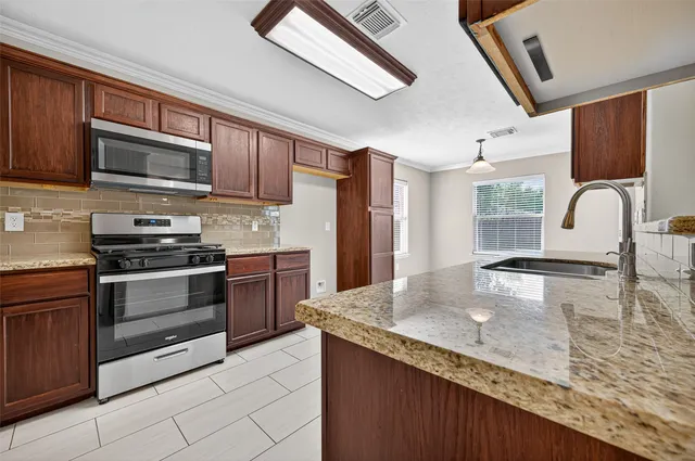 a kitchen with stainless steel appliances granite countertop a sink stove and microwave