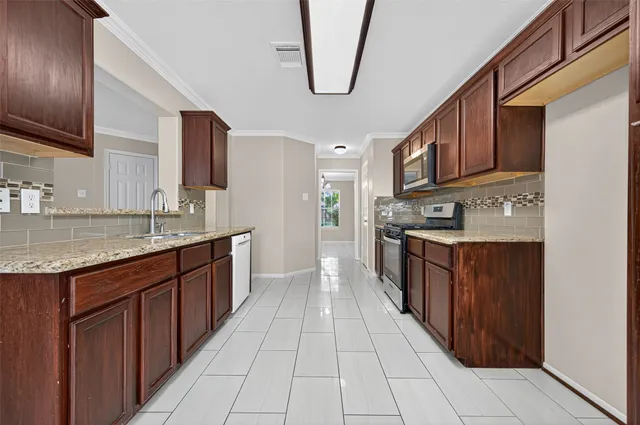 a large kitchen with stainless steel appliances granite countertop a stove a sink dishwasher and a refrigerator