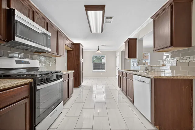 a kitchen with stainless steel appliances granite countertop a stove a sink and a microwave
