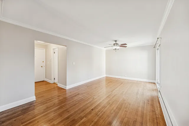 an empty room with wooden floor ceiling fan and windows