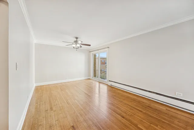 an empty room with wooden floor chandelier fan and windows