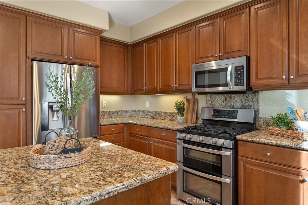 28817 Edenton Way Temecula, CA 92591 - Photo 23 of 56 a kitchen with granite countertop wooden cabinets and a stove top oven