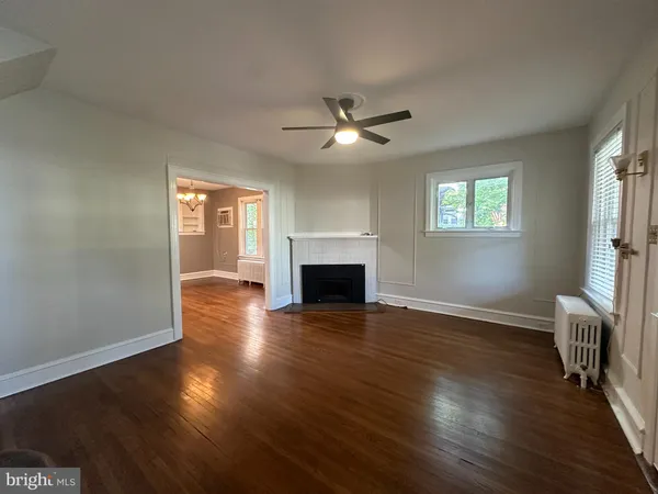an empty room with wooden floor fireplace and windows